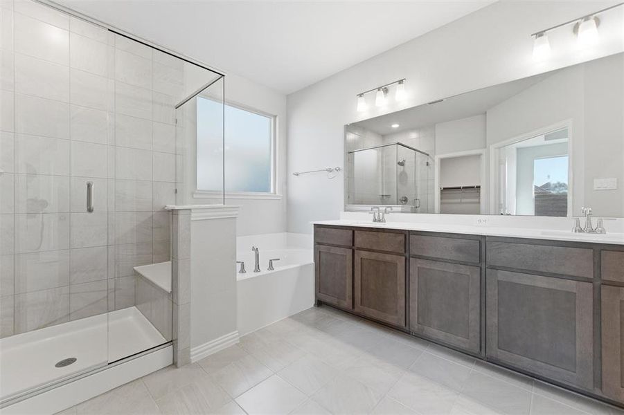 Full bathroom featuring double vanity, a spacious closet, a shower stall, a bath, and light tile patterned floors