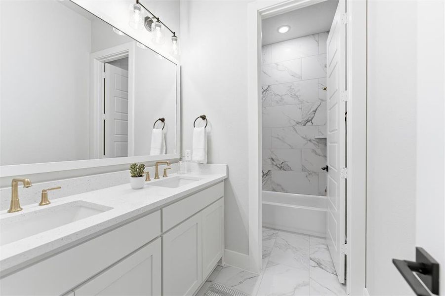 Bathroom featuring light marble finish floors, double vanity, and shower / tub combination