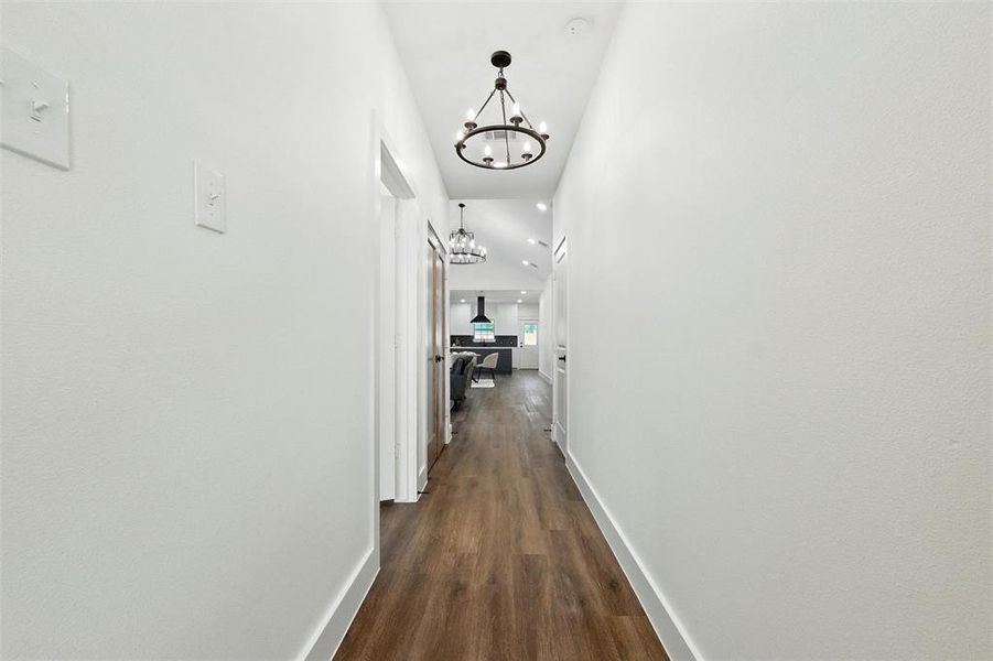 Corridor with a chandelier and dark wood finished floors