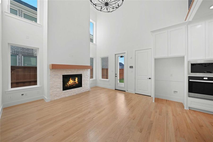 Unfurnished living room with light wood finished floors, a fireplace, and a high ceiling Unfurnished living room with light wood finished floors, a fireplace, and a high ceiling