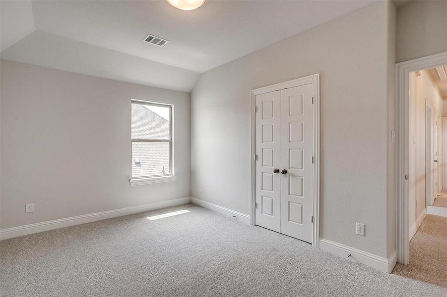 Unfurnished bedroom with light colored carpet, lofted ceiling, and a closet