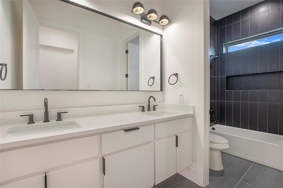 Full bathroom featuring vanity, tiled shower / bath combo, toilet, and tile patterned floors