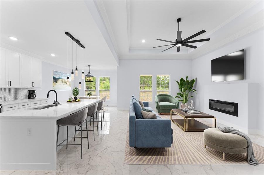 Living room featuring crown molding, a tray ceiling, sink, and ceiling fan