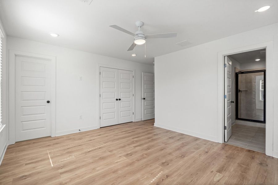 Recessed lighting, wood-finish flooring, ceiling fan, bi-fold closet doors, and an en-suite bathroom with a glass shower enclosure