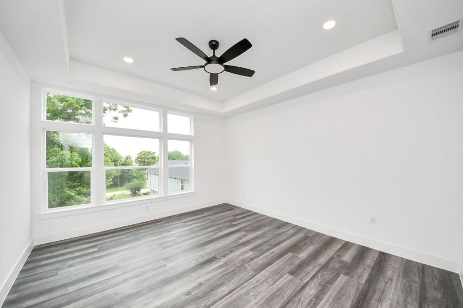Bright, spacious room featuring large windows with a scenic view, modern gray flooring, and a ceiling fan with recessed lighting. Ideal for a bedroom or living area. Bright, spacious room featuring large windows with a scenic view, modern gray flooring, and a ceiling fan with recessed lighting. Ideal for a bedroom or living area.