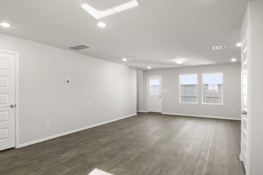Image of a dining area with dark brown vinyl flooring, light grey walls, two windows and white trim