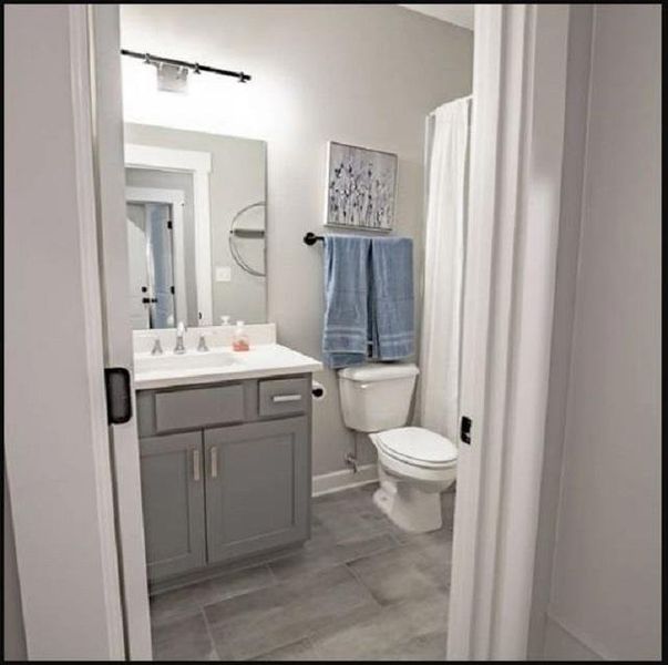Bathroom featuring a gray vanity with white countertop, chrome fixtures, tile flooring, and a white toilet