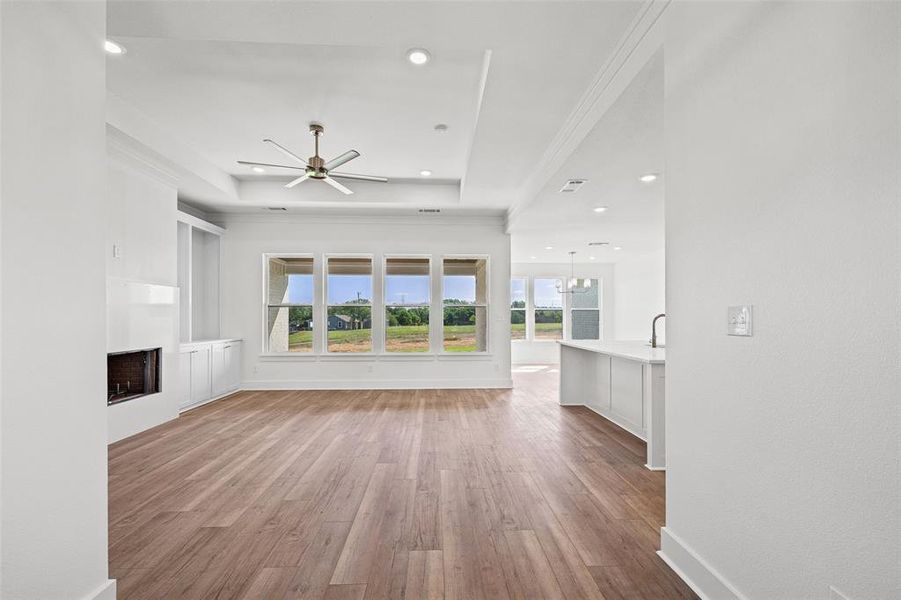 Spacious living area featuring wood-finish flooring, a contemporary fireplace with built-in cabinetry, large windows, recessed lighting, and a ceiling fan
