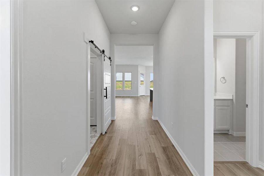 Hallway featuring wood-finish flooring, recessed lighting, and a modern barn door