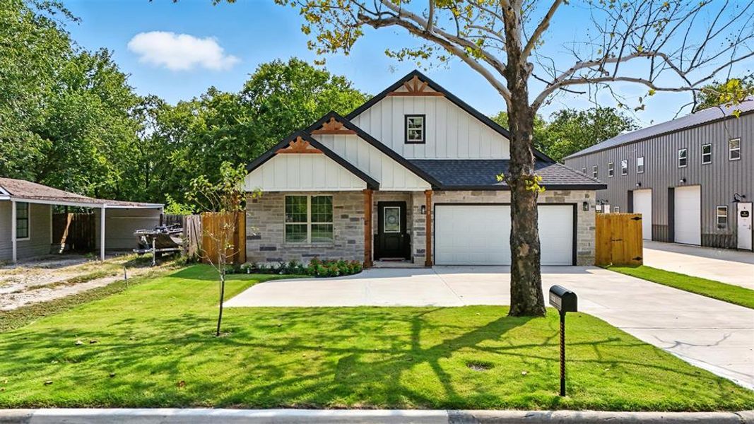 View of front of property with board and batten siding, a garage, a shingled roof, concrete driveway, and stone siding