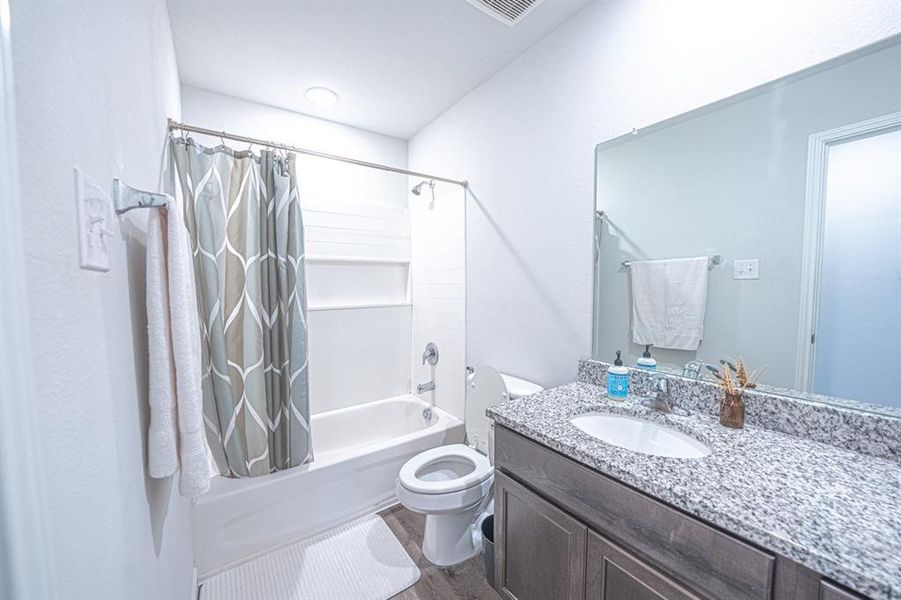 Full bath featuring shower / bath combination with curtain, dark wood-style floors, and vanity
