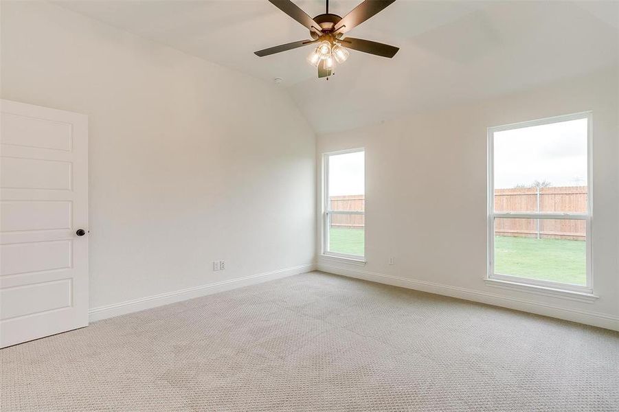 Carpeted empty room featuring ceiling fan and lofted ceiling