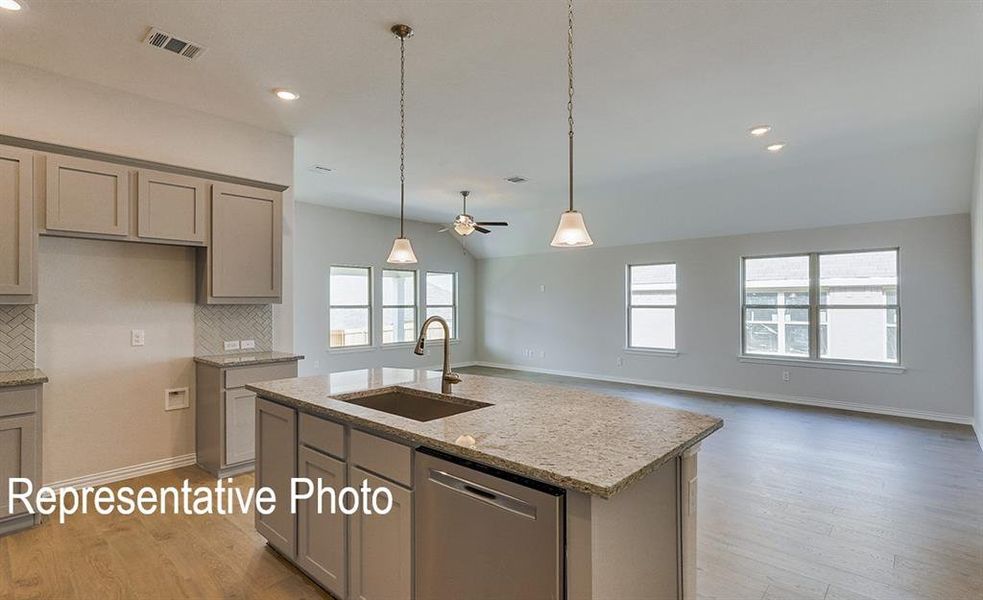 Kitchen island featuring a stainless steel sink, pull-down faucet, and integrated dishwasher