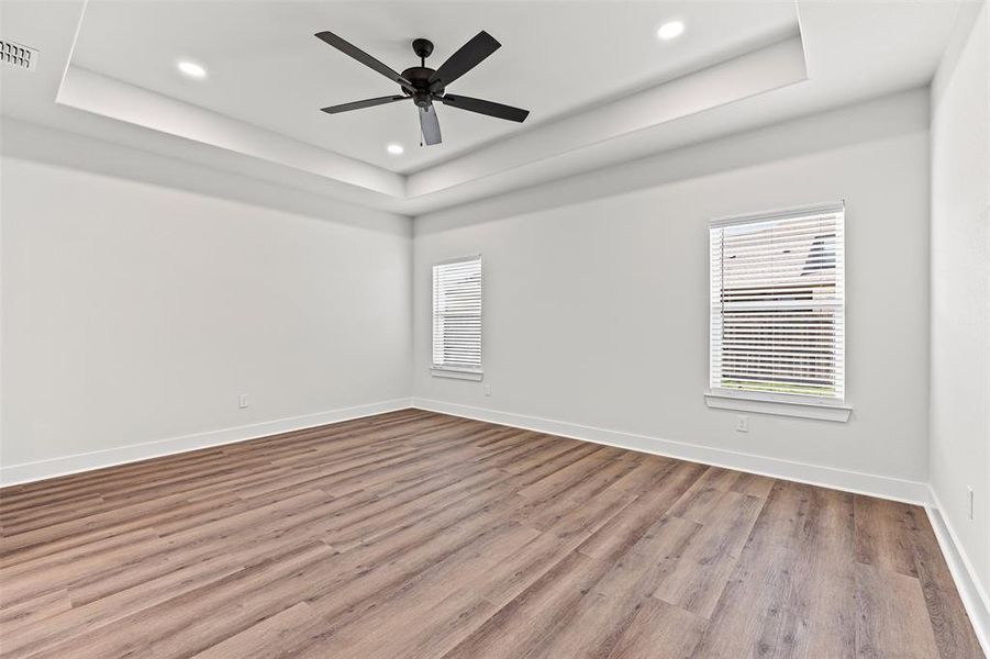 Unfurnished bedroom featuring a tray ceiling, light wood-style flooring, and recessed lighting Unfurnished bedroom featuring a tray ceiling, light wood-style flooring, and recessed lighting