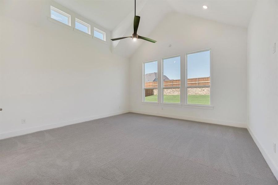 Spare room featuring healthy amount of natural light, high vaulted ceiling, light colored carpet, and ceiling fan