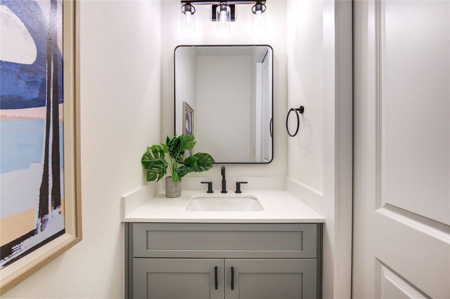 Elegant half bathroom featuring modern fixtures, sleek vanity, and a chic mirror, perfect for guests.
