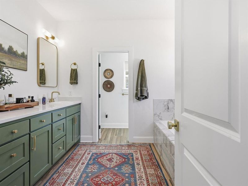Full bathroom featuring double vanity, dark wood finished floors, and tiled bath