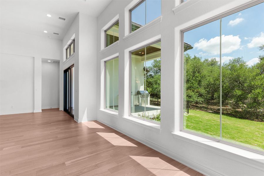 Floor-to-ceiling windows illuminate the inviting interior, offering scenic views of the lush, green yard.