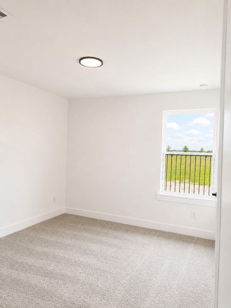 Cozy additional bedroom featuring soft neutral colors, plush carpeting, and natural light creating a warm and inviting space.