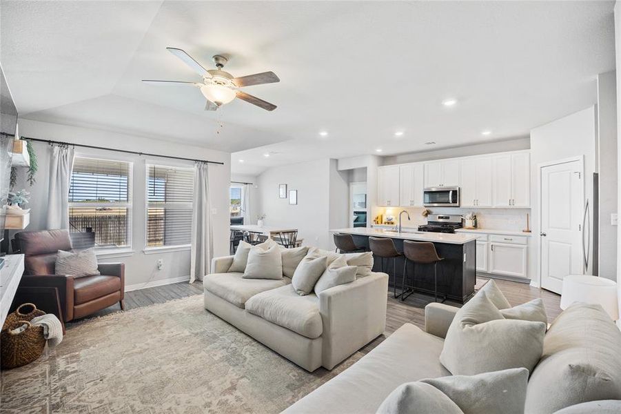 Living area featuring light wood-type flooring, a ceiling fan, lofted ceiling, and recessed lighting