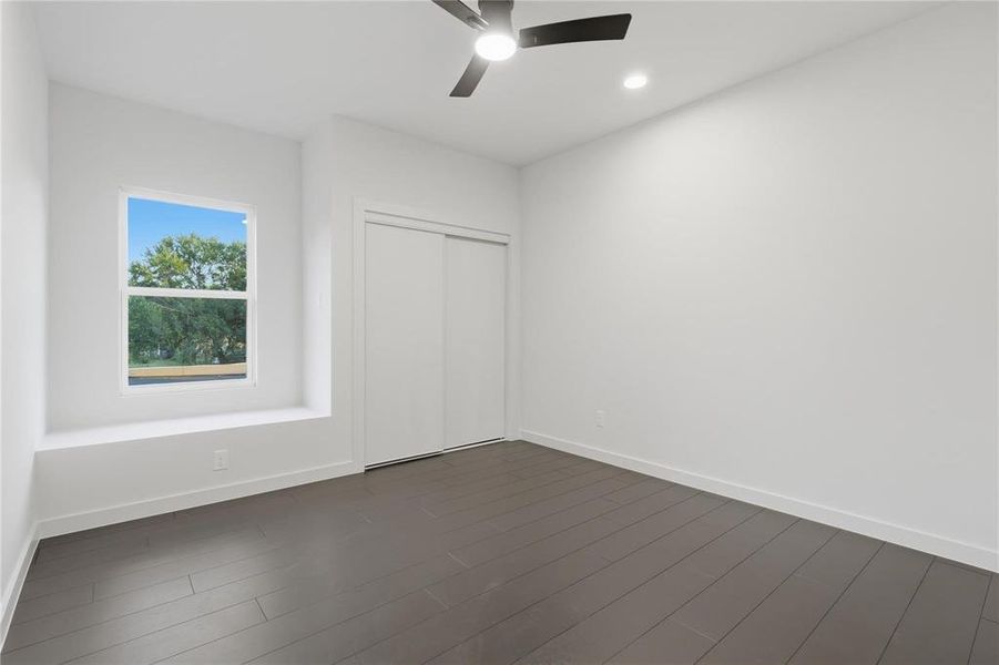 Bright room featuring dark wood-finish flooring, a contemporary ceiling fan, and recessed lighting