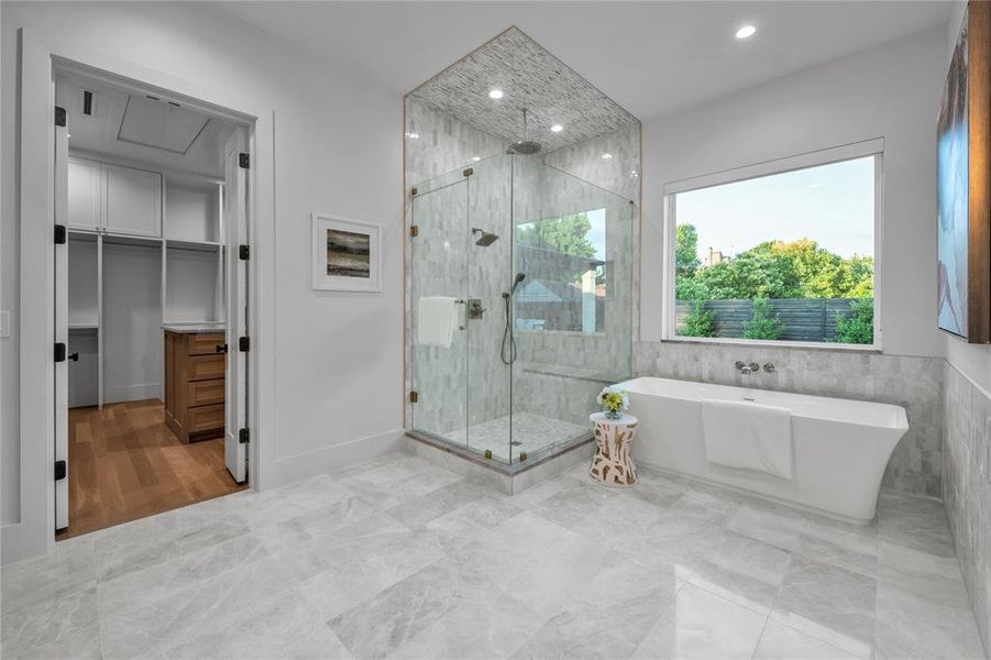 Full bathroom with a freestanding tub, a stall shower, a spacious closet, recessed lighting, and tile walls Full bathroom with a freestanding tub, a stall shower, a spacious closet, recessed lighting, and tile walls