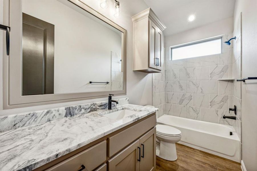 Full bathroom with vanity, toilet, hardwood / wood-style flooring, and tiled shower / bath