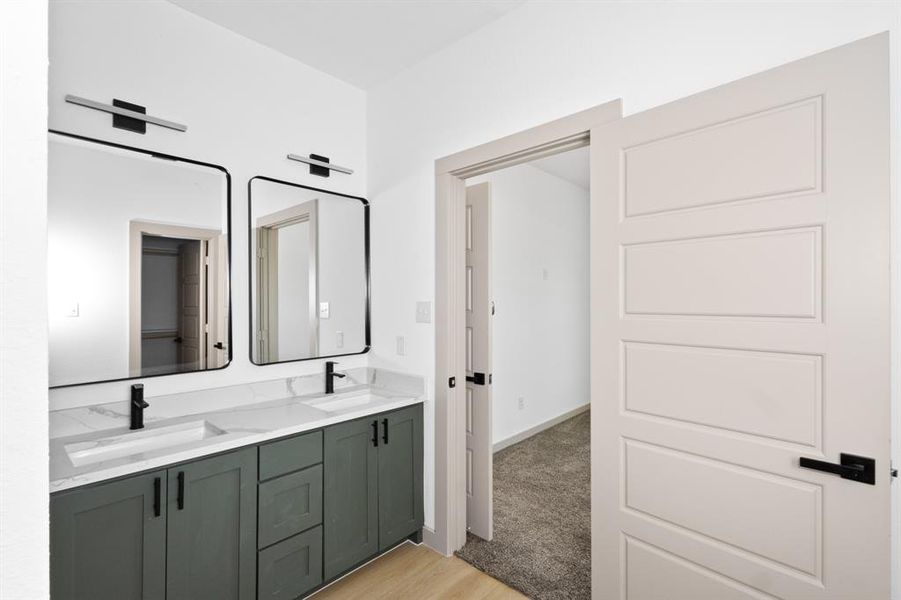 Full bathroom with double vanity, wood finished floors, and a sink Full bathroom with double vanity, wood finished floors, and a sink