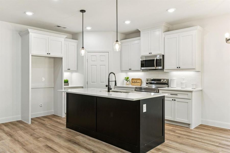 Kitchen featuring dark cabinets, pendant lighting, white cabinetry, appliances with stainless steel finishes, and recessed lighting