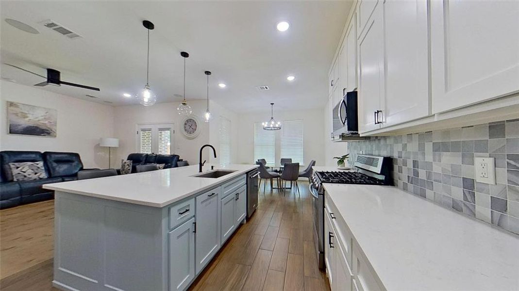Kitchen featuring appliances with stainless steel finishes, decorative light fixtures, open floor plan, white cabinetry, and recessed lighting