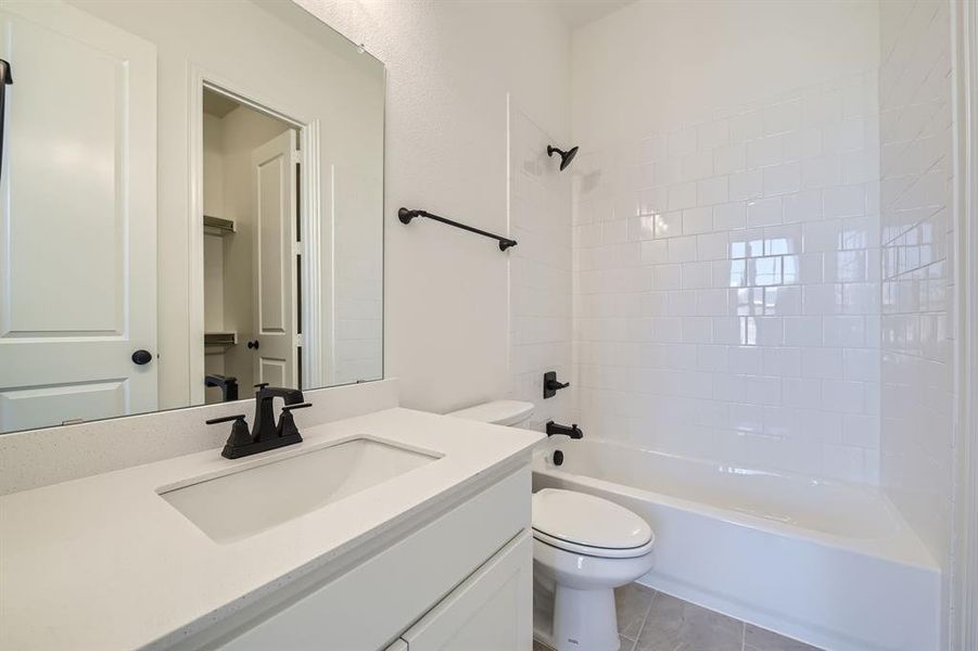 Full bathroom featuring vanity, tile patterned flooring, toilet, and tiled shower / bath