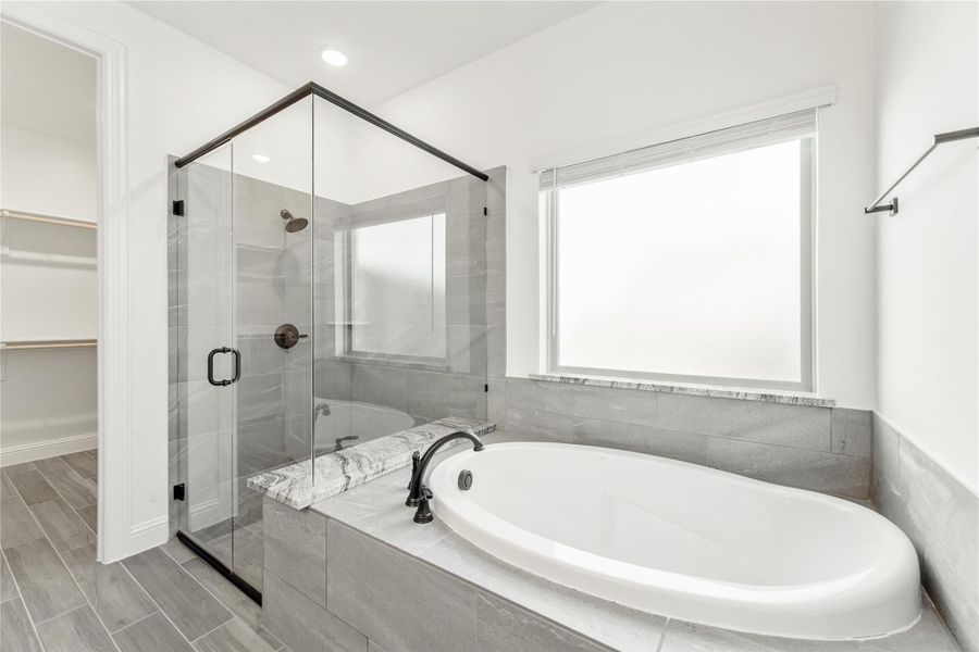 Master bathroom with soaking tub, glass-enclosed shower, gray tile walls, and wood-look floor tiles Master bathroom with soaking tub, glass-enclosed shower, gray tile walls, and wood-look floor tiles