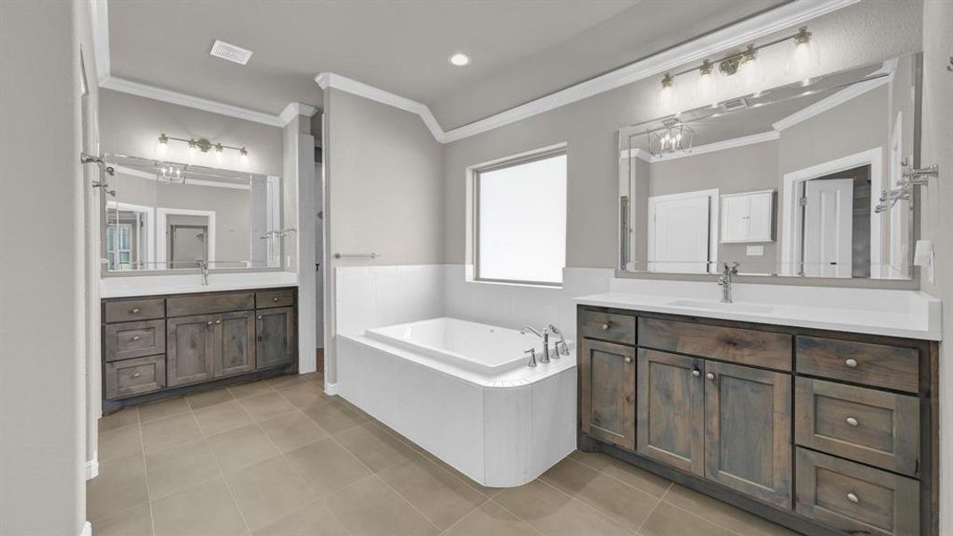 Spacious Primary Bathroom with tile patterned flooring, a bathtub, ornamental molding, and vanity