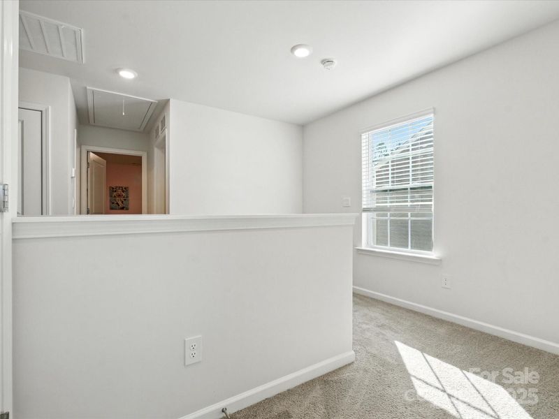 Spacious open hall upstairs. Large window and neutral walls create flexible space that could serve as bedroom, office, or family room.