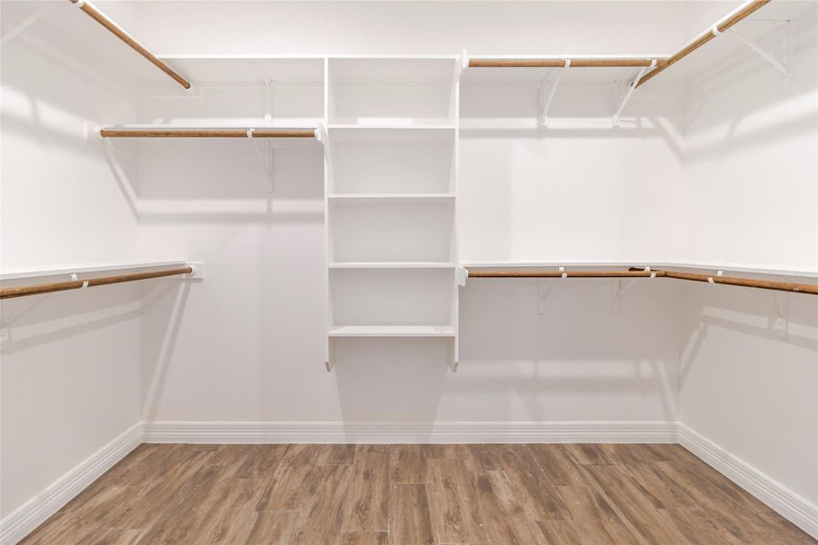 Shelving and hanging space wrap around three sides of the walk-in closet, leaving the center open and usable. Shelving and hanging space wrap around three sides of the walk-in closet, leaving the center open and usable.