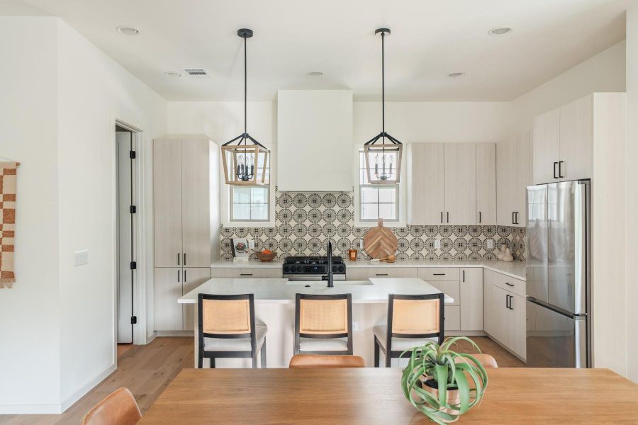 Kitchen with stainless steel appliances, decorative light fixtures, a breakfast bar, tasteful backsplash, and light wood-type flooring
