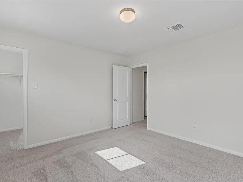 A spacious, neutral-toned room awaits personalization with its soft carpet and bright overhead lighting.