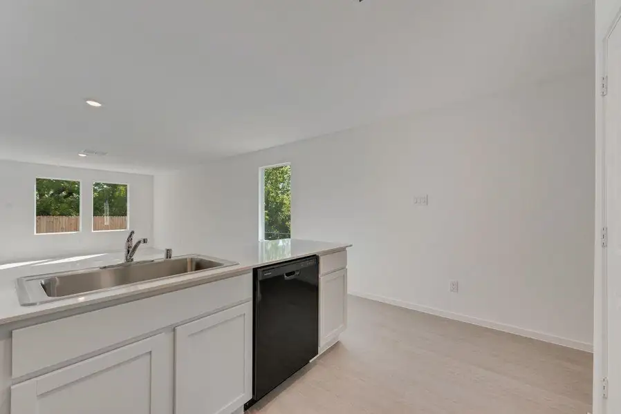 Kitchen with white cabinetry, black dishwasher, light wood-style flooring, recessed lighting, and light stone countertops