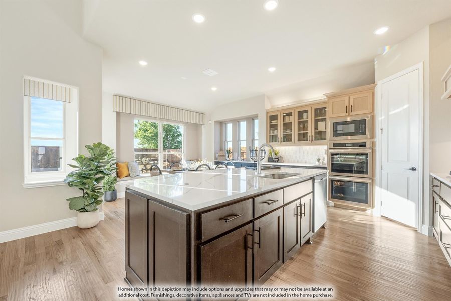 Kitchen with dark island, white quartz countertop, stainless steel double ovens, and light wood floors open to dining area Kitchen with dark island, white quartz countertop, stainless steel double ovens, and light wood floors open to dining area