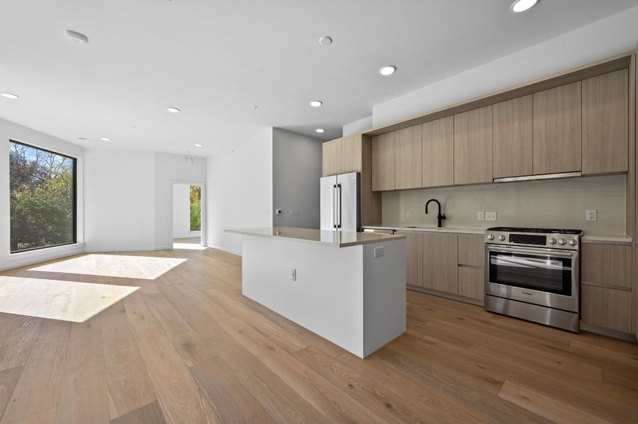 Kitchen with modern cabinets, stainless steel appliances, recessed lighting, light wood finished floors, and open floor plan Kitchen with modern cabinets, stainless steel appliances, recessed lighting, light wood finished floors, and open floor plan