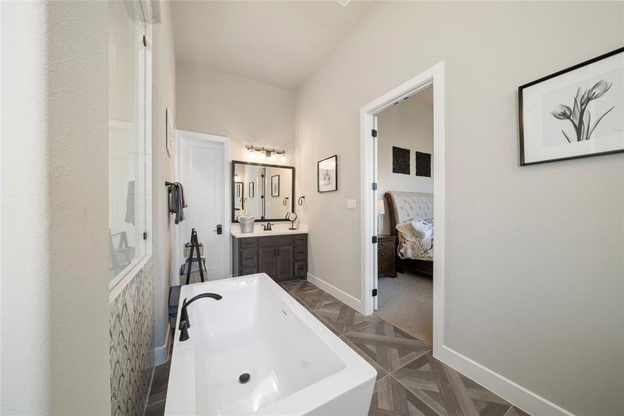 Bathroom featuring parquet flooring, vanity, and a bathtub