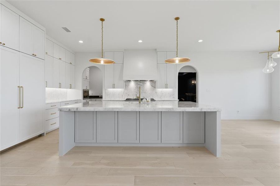 Central kitchen island with a waterfall countertop, accented by brass pendant lighting