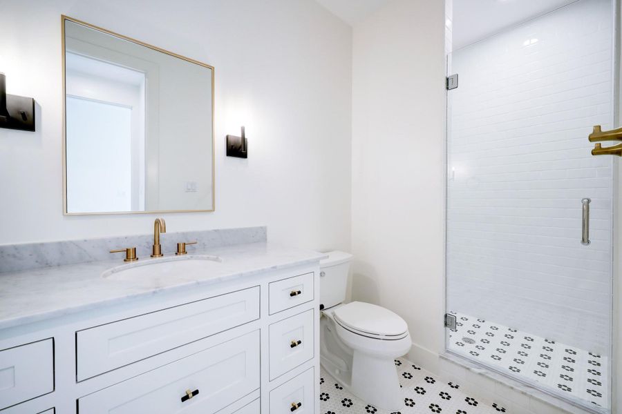 Secondary bathroom shared with Bedroom #3 and the game room. A large vanity with ample storage is complimented by black and gold knobs and a gold framed mirror. A decorative tile is carried through the bathroom and shower floor. *Previous Proiect*