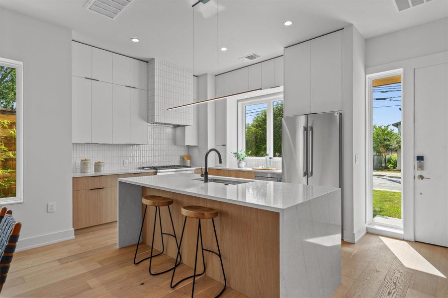 The stunning kitchen features a center island with quartz waterfall edge. The stunning kitchen features a center island with quartz waterfall edge.