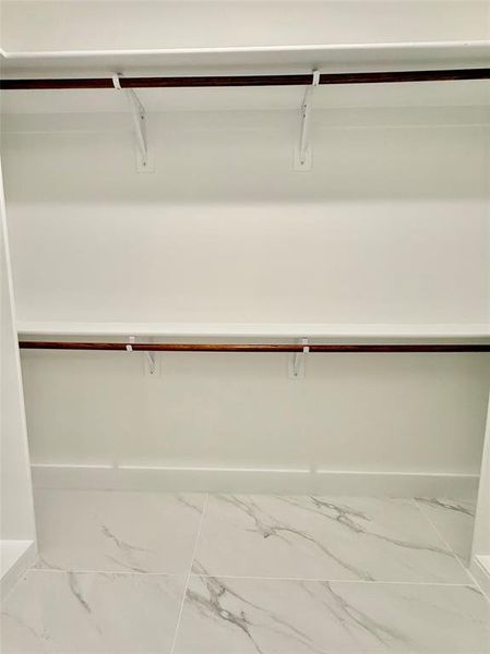 Walk in closet featuring marble look tiles