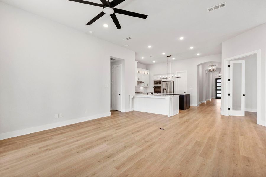 Open-concept living with wide-plank floors, sleek kitchen island, and statement pendant lighting throughout.