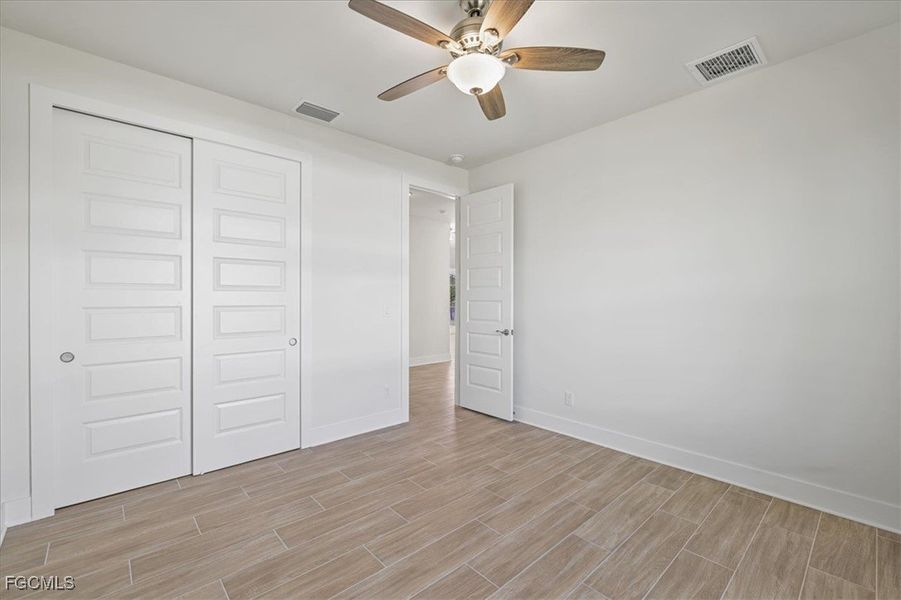 Unfurnished bedroom featuring wood finish floors, a closet, and ceiling fan