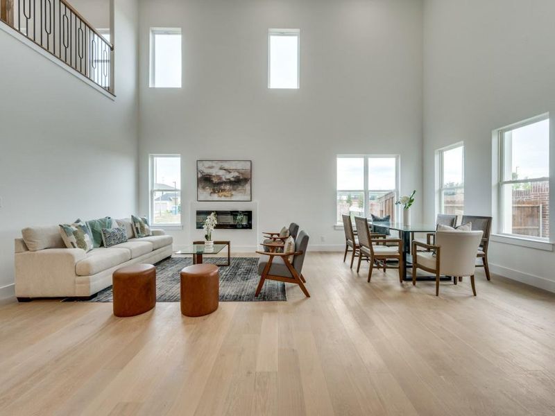 Living room with a towering ceiling, plenty of natural light, and light wood-type flooring