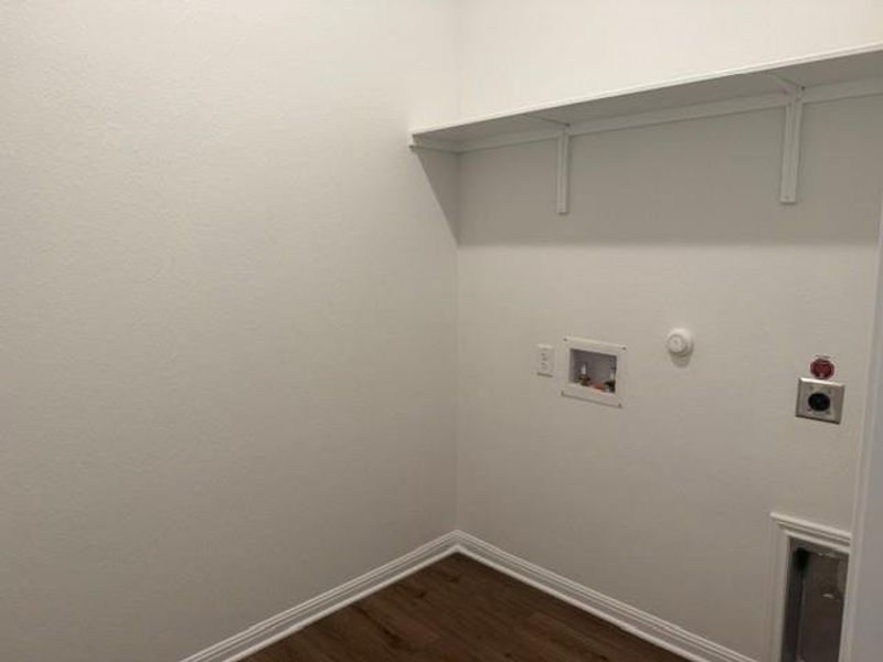 Dedicated laundry area featuring wood-finish flooring, white baseboards, and bright white walls