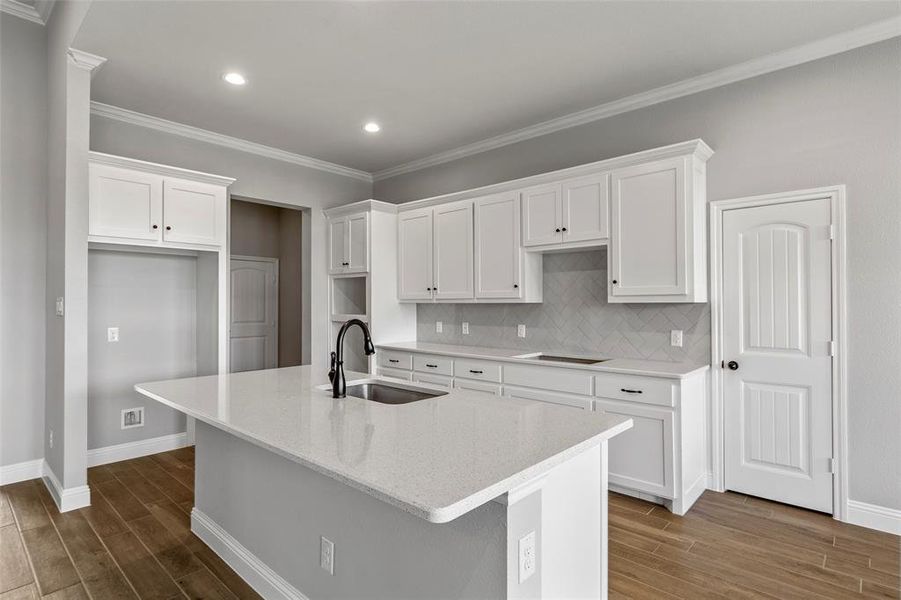 Kitchen featuring white cabinetry, a kitchen island with sink, and sink